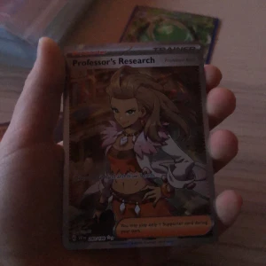 Pokémonkort - Professor's Research - Säljer ett Pokémonkort med motivet 'Professor's Research'. Kortet är en supporter-tränarkort med en färgglad design och visar en karaktär i en vit och orange outfit. Perfekt för samlare eller spelare som vill förstärka sin kortlek.