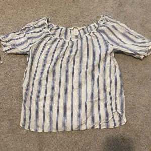 Blus - En vacker somrig blus som passar perfekt för sommaren. Den har blåa stripes vilket ger den en trendig look