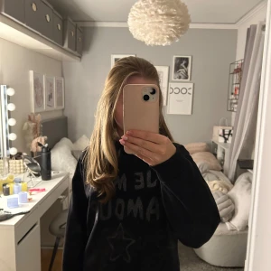 Svart hoodie med text - Säljer en svart hoodie med text' i glittriga bokstäver på framsidan. Tröjan har långa ärmar och en stjärna under texten. Perfekt för en avslappnad stil.