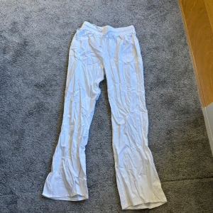 Vita byxor med broderad detalj - Snygga vita byxor med elastisk midja och broderad hjärtdetalj. Perfekta för en avslappnad stil. Byxorna har en loose passform och är tillverkade i ett lätt material.