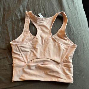 Beige sporttopp från hm - Säljer en beige sporttopp från Love med brottarrygg och elastisk nederkant. Perfekt för träning och ger bra stöd. Materialet är mjukt och stretchigt för maximal komfort.