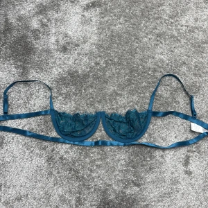 Blå spets-bh - Säljer en elegant blå bh med spetsdetaljer. Den har tunna axelband och en delikat design som ger en feminin touch. Perfekt för att känna sig extra fin.