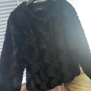Svart pälsjacka från Vero Moda - Säljer en snygg svart pälsjacka från Vero Moda. Jackan har en mjuk och fluffig yta med knappar framtill. Perfekt för att hålla sig varm och stilren under kyliga dagar.