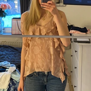 Beige/rosa blommig topp från Zara - Säljer en söt beige/rosa topp från Zara i XS med blommigt mönster och volangdetaljer. Jätte fint skick då jag endast använt den ett fåtal gånger, hör av er vid fler frågor💞