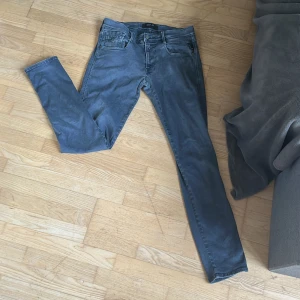 Grå jeans från Replay - Snygga grå jeans från Replay med en klassisk femficksdesign. De har en knappgylf och är tillverkade i ett slitstarkt material. Perfekta för en stilren look.