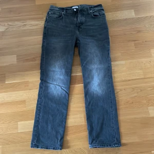 Grå/svarta jeansbyxor - Snygga grå jeansbyxor med en klassisk straight passform. Byxorna har en dragkedja och knapp framtill samt fem fickor. Perfekta för en avslappnad stil.