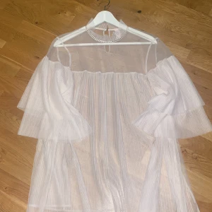 Vit transparent klänning från Victoria's secret  - Säljer en elegant vit transparent klänning från Victoria's Secret. Klänningen har långa ärmar och en hög hals med knytning i nacken. Perfekt för en stilfull look.