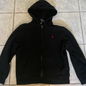 Polo ralph lauren hoodie  - Polo ralph lauren hoodie i väldigt bra skick. Inte använd så mycket då den blivit för liten. Finns inga hål/fläckar eller liknande, enda defekten är att lappen vid nacken har lossnat på ena sidan (bild kan fixas) men inget som syns under användning! 
