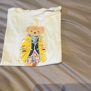 Rapphöna lauren T-shirt  -  Jättegullig vi drar från en tröja med en björn på med  en gul kappa med broderade  detaljer