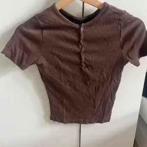 Brun t-shirt med knappar från Gina tricot - Bra skick använd fåtal gånger 