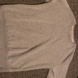 Grå tröja - Säljer en enkel och bekväm grå tröja. Perfekt för vardagsbruk med sin mjuka och sköna känsla. Tröjan har korta ärmar och en normal passform. Passar bra till både jeans och mjukisbyxor.