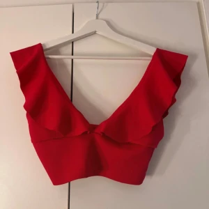 Röd volang crop top Nelly - Röd topp köpt från Nelly i märket NLY One. Sitter väldigt smickrande me volangerna tillsammans med den öppna ryggen❣️