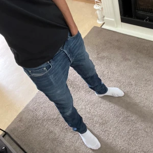 Blå jeans med knappar - Säljer ett par snygga blå jeans i bra skick. De har en klassisk femficksdesign och stängs med knappar framtill. Jeansen har en lätt tvättad look som ger dem en cool och avslappnad stil. Perfekta för vardagsbruk! Passar mig som är 180 ungefär 