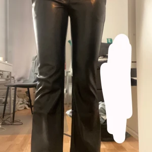 Svarta skinnbyxor - Snygga svarta skinnbyxor med bootcut-stil. Perfekta för en trendig look med en glansig finish. Passar bra till både vardag och fest.