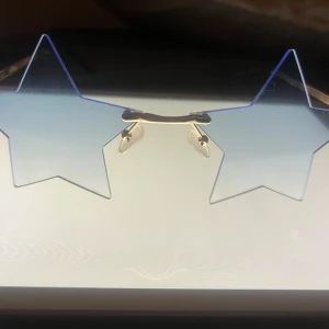 y2k star solglasögon  - Coola y2k  stjärnformade solglasögon med blåtonade linser och guldfärgade detaljer. Perfekta för att sticka ut och ge en unik touch till din stil. De har justerbara näskuddar för extra komfort.