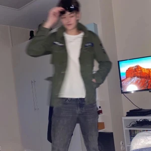 Grön militärinspirerad jacka - Säljer en grön militärinspirerad jacka med broderade detaljer och dragkedja. Jackan har en normal passform och är långärmad, perfekt för höst och vår. Den har en cool och avslappnad stil.