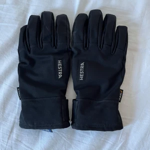 Svarta handskar från Hestra - Säljer ett par svarta Hestra-handskar i storlek 7. De är tillverkade i slitstarkt material med justerbara muddar och har en stilren design. De är i bra skick. Skriv vid frågor. Mvh Eric