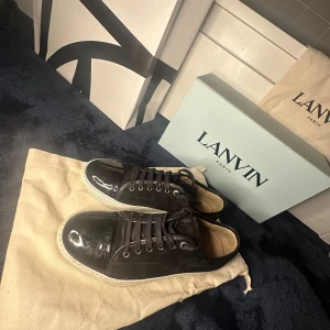Svarta sneakers från Lanvin - Snygga svarta sneakers från Lanvin med en stilren design. Skorna har en blank tå och snörning framtill. Perfekta för en trendig look.