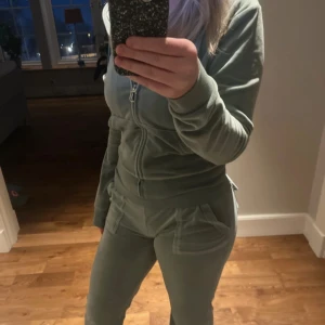 Ljusgrön Juicy Couture sett - Säljer ett mysigt ljusgrönt juice couture sätt. Kläderna är i bra skick men byxfickan är lite sönder och en metallbit på snöret har ramlat av. Storleken stämmer bra, tröjan är i s och byxorna i xs