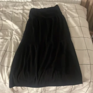 Svart kjol från Kappahl - Snygg svart kjol från Kappahl i en klassisk design. Kjolen har en enkel och stilren look som passar perfekt till olika tillfällen. Den är gjord i ett mjukt och bekvämt material som ger en skön passform.