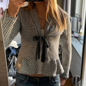 Mönstrad kofta från Odd Molly - Säljer en snygg mönstrad kofta från Odd Molly i svart och vit. Jackan har långa ärmar och en knytning framtill. Den har ett unikt mönster och volangdetaljer vid nederkanten. Skulle säga att storleken är S/M