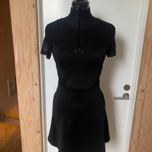 Svart klänning med korta ärmar - Elegant svart klänning med korta ärmar och en figurnära passform. Riktig 2016 vibe på bästa sättet med mesh detalj över bysten.