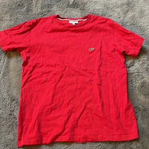 Röd t-shirt från Lacoste - Snygg röd t-shirt från Lacoste med det klassiska krokodilmärket broderat på bröstet. Storlek 164 men passar xs. Original pris 550kr