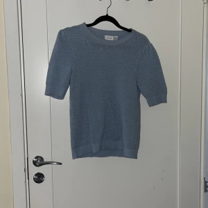Ljusblå stickad tröja från VILA - Säljer en ljusblå stickad tröja från VILA i storlek XS. Tröjan har korta ärmar och ett fint stickat mönster som ger en stilren look. Perfekt för vår och sommar!