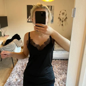 Svart linne med spetsdetaljer - Super snyggt svart linne med smala axelband och vacker spetsdetalj vid halsringningen. 