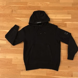 Svart hoodie från C.P. Company - Säljer en stilren svart hoodie från C.P. Company då den inte används. Storlek M 