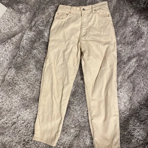 Beige byxor från Woodbird - Snygga beige byxor från Woodbird i en klassisk stil. De har en mer baggy passform och är tillverkade i ett bekvämt material. Perfekta för en stilren look. Köptes för ungefär 1100-1200kr från The Local Store.