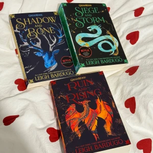 Grisha-trilogin av Leigh Bardugo - Säljer Grisha-trilogin av Leigh Bardugo, inklusive 'Shadow and Bone', 'Siege and Storm' och 'Ruin and Rising'. Böckerna har färgglada omslag med fantasy-tema och är perfekta för fans av magiska äventyr. Serien är även känd från Netflix.