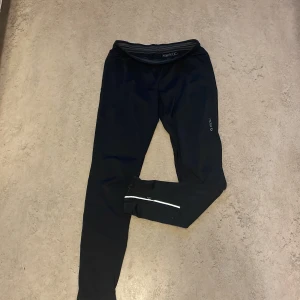 Svarta Träningsbyxor  - Säljer ett par träningsbyxor i storlek M och märket är SOC. Det har nät vid knävecket samt resår i midjan och vid slutet av benen finns både resår och reflex samt blixtlås. Det är lite slitna på SOC trycket. 
