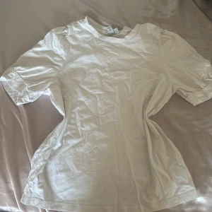 Vit t-shirt med puffiga armar från Vero Moda - Säljer en stilren vit t-shirt från Vero Moda, kollektionen AWARE.  Har använts 2 gånger.T-shirten har korta puffiga ärmar och är tillverkad i ett mjukt material. Perfekt till att styla med vad som helst , den behöver dock strykas. Swisha till 0720368146 för att köpa , för att min Swish funkar ej