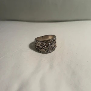 Silverfärgad ring med stenar - Elegant men cool silverfärgad ring med intrikata detaljer och mönster som sticker ut. Perfekt för att ge en stilfull touch till din outfit.