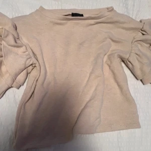 Beige tröja med volangärmar från Varlsca - Säljer en stilren beige tröja från Varlsca med volangdetaljer på ärmarna. Tröjan har en mjuk och bekväm passform. Bara andvänd 1 gång för kände inte attbjag riktigt passar i den🤩