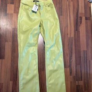 Limegröna byxor från Bik Bok - Snygga limegröna byxor från Bik Bok i syntetmaterial. De har en hög midja och raka ben med en klassisk femficksdesign. Perfekta för att ge en färgklick till din outfit. Helt nya med prislapp kvar på. Nypris 499kr.