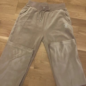 Beige mjukisbyxor från Juicy Couture - Beige mjukisbyxor från Juicy couture knappt använda, glittrande detaljer. Snörning i midjan.