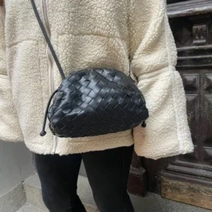 Svart flätad axelväska - Snygg svart axelväska med flätat mönster och justerbar axelrem. Perfekt för att ge en stilren touch till din outfit. Väskan är kompakt men rymmer det viktigaste du behöver ha med dig.