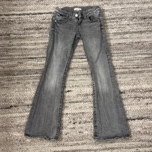 Grå bootcut jeans från Gina Tricot - Snygga grå bootcut jeans från Gina Tricot i storlek 140. De har en klassisk femficksdesign och en knapp med dragkedja framtill. Perfekta för en avslappnad stil❤️