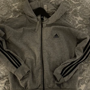 Grå hoodie från Adidas - Säljer en grå hoodie från Adidas med dragkedja skit snygg storlek S
