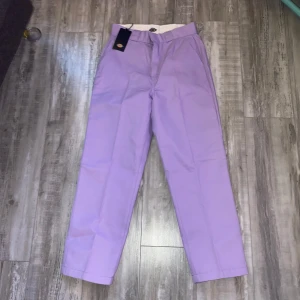 Lila byxor från Dickies - Finns 2 par. I storlek 27 och 29. !!priset gäller för ett par!! Aldrig använt, prislappen sitter kvar på byxorna. Perfekt till våren med pastellfärger! lila byxor från Dickies med en klassisk design. Byxorna har en rak passform och är tillverkade i ett slitstarkt material. Perfekta för en stilren look. 