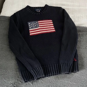 Ralph Lauren Stickad Tröja - Säljer denna eftertraktade och unika Ralph Lauren Flag Knit. Tröjan är i storlek L (14-16), vilket motsvarar XS ungefär. Tröjan har inga defekter och är i ett toppen skick!