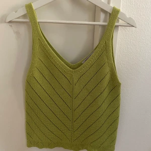 Grön stickad linnetopp - Snygg grön stickad linnetopp med v-ringning och ett diskret mönster. Perfekt för varma dagar och kan enkelt matchas med olika outfits.