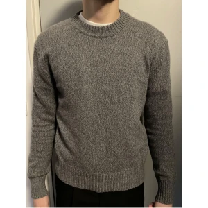 Ami Paris tröja oanvänd - Säljer en stilren grå stickad tröja från Ami. Tröjan har en klassisk rund halsringning och långa ärmar. Perfekt för kyligare dagar och passar till många olika outfits. Ett måste i garderoben för den som gillar enkel och tidlös design. Skriv vid frågor!