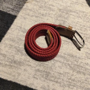 Rött flätat bälte med silverfärgat spänne - Snyggt vin rött flätat bälte med ett stilrent silverfärgat spänne. Bältet har detaljer i brunt skinn vid spännet som ger en extra touch av elegans. Perfekt för att ge din outfit en färgklick. De är typ ett halv år gammalt och kostade 200kr jag säljer de för 100kr. 