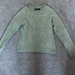 Grön stickad tröja från Vero Moda - Säljer en mysig grön stickad tröja från Vero Moda. Tröjan har en klassisk rund hals och långa ärmar, perfekt för kyligare dagar. Den är enkel och stilren, vilket gör den lätt att matcha med olika outfits. Perfekt för både vardag och avslappnade tillfällen.