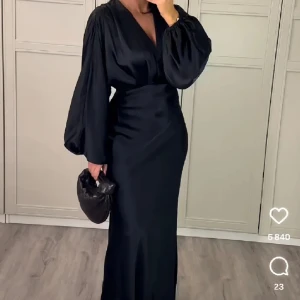 Svart långklänning från Gina Tricot - Elegant svart långklänning från Gina Tricot med v-ringad hals och långa ballong ärmar. Klänningen har en smickrande passform och är tillverkad i ett satin material. Perfekt för speciella tillfällen som till exempel bal/middag/fest. Använd endast 1 gång och slutsåld! Har en liten ”defekt” vid bysten men inget som läggs märke till 💕