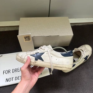 Golden goose sneakers - Säljer ett par sjukt snygga Golden goose superstar sneakers i den eftertraktade modellen navy & white. Nypris 5800kr. Allt OG ingår vid köp: Dustbag, originalbox, GG passport och kvitto. Storlek 40 men sitter något större. Kom med prisförslag!!!🤝