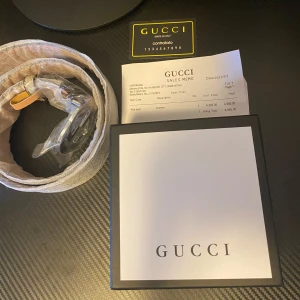 Gucci bälte med GG-spänne - Säljer ett snyggt Gucci bälte i nytt skick. Det har ett stort, glänsande GG-spänne i silver och ett klassiskt mönster i beige och brunt. Perfekt för att lyfta vilken outfit som helst! Kommer med originalförpackning och kvitto.